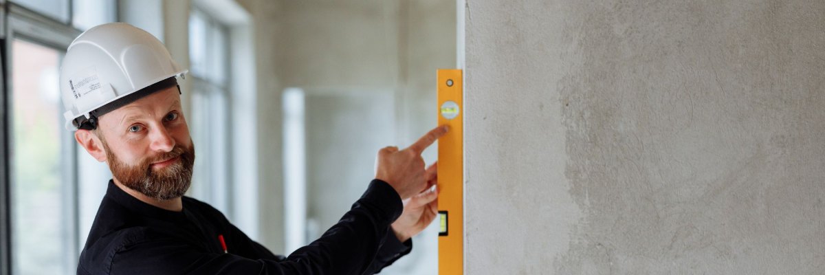 Un responsable de projet casqué contrôle un mur dans un immeuble en chantier